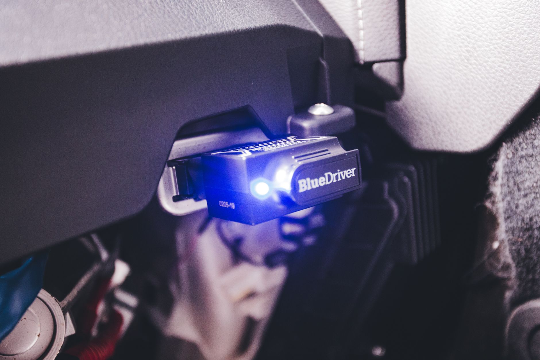 Code scanner plugged into a car's diagnostic port under the dashboard