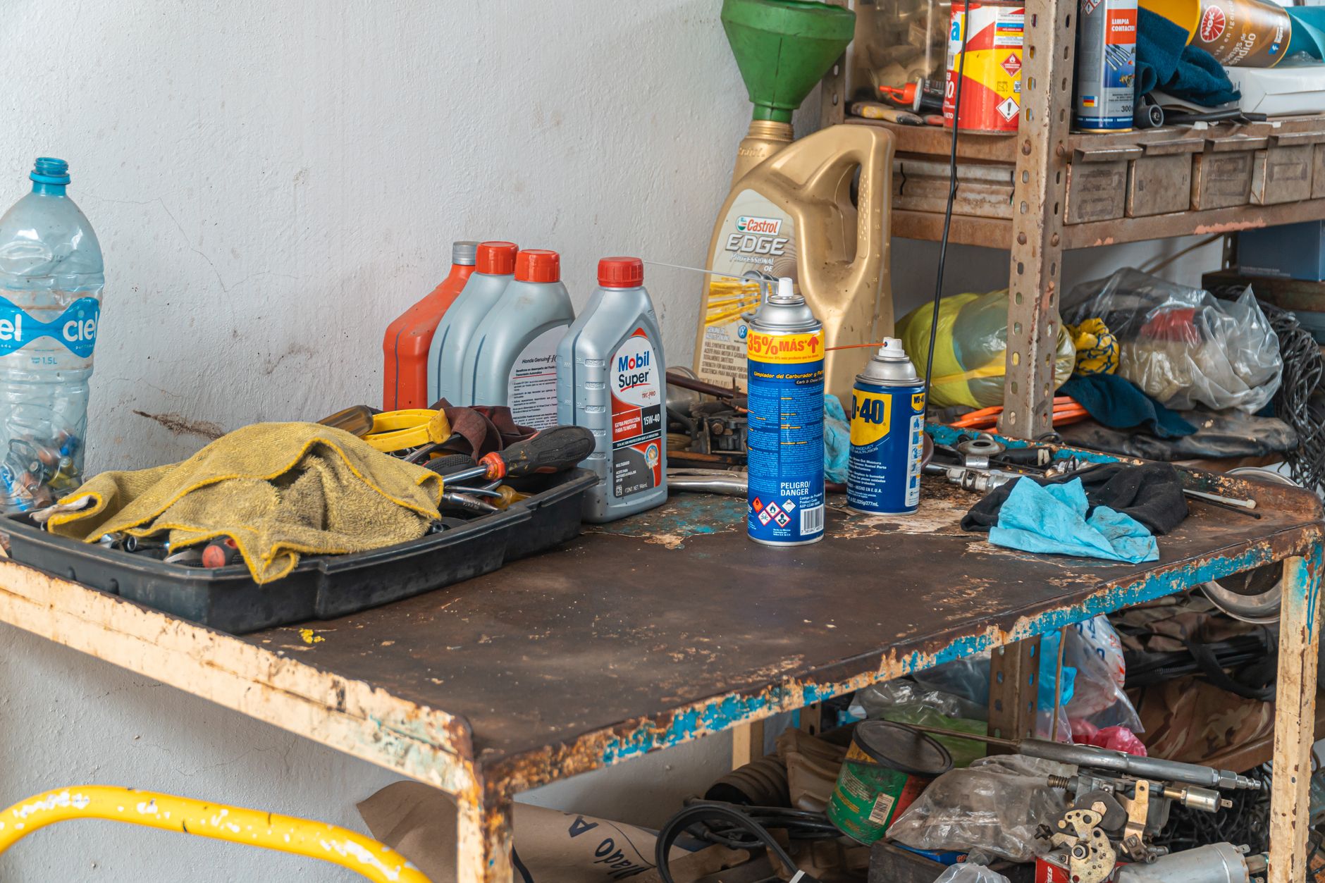 Garage workbench with bottles of automotive fluids, tools and gloves