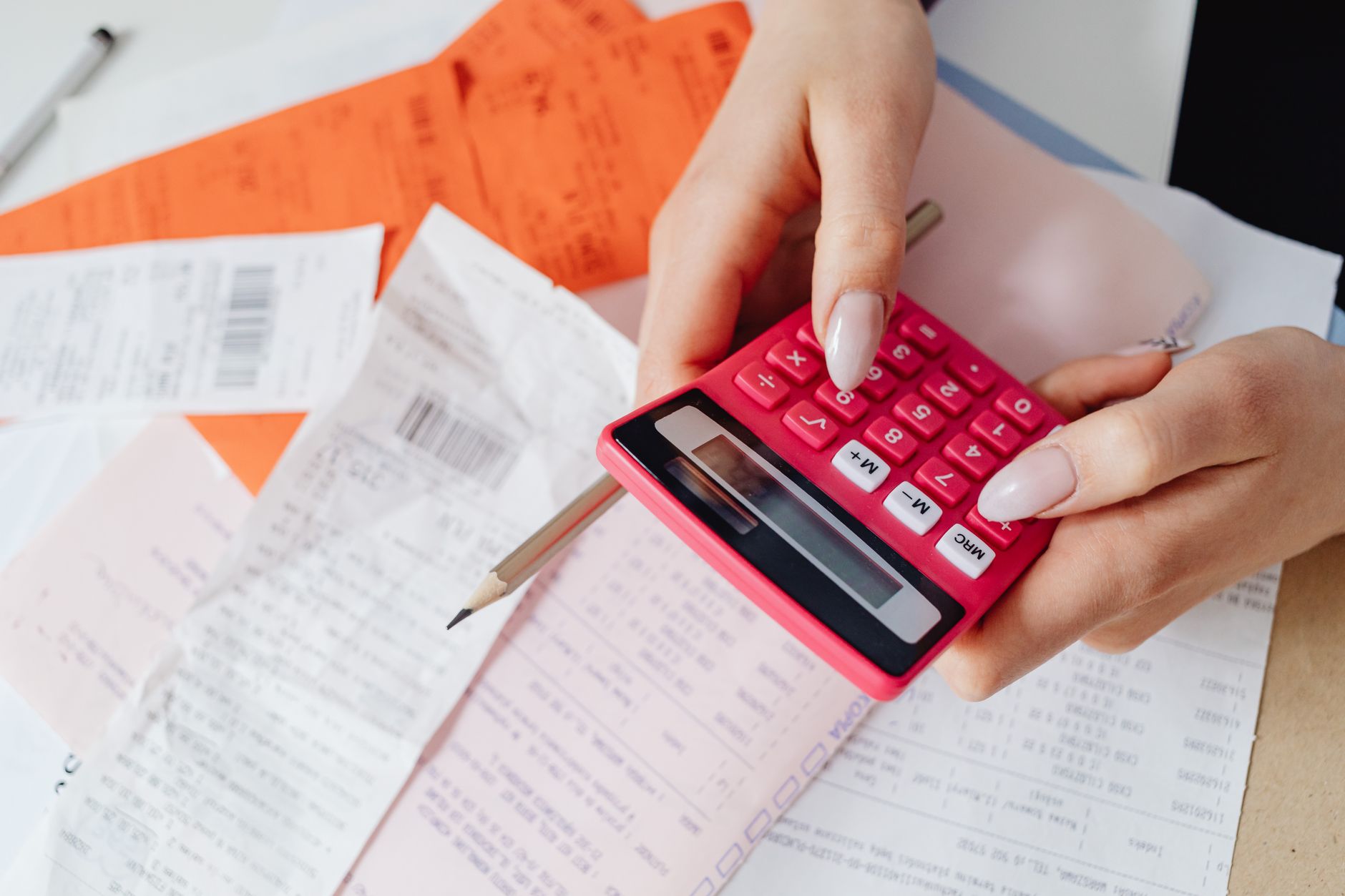 Hands using a calculator over a pile of receipts