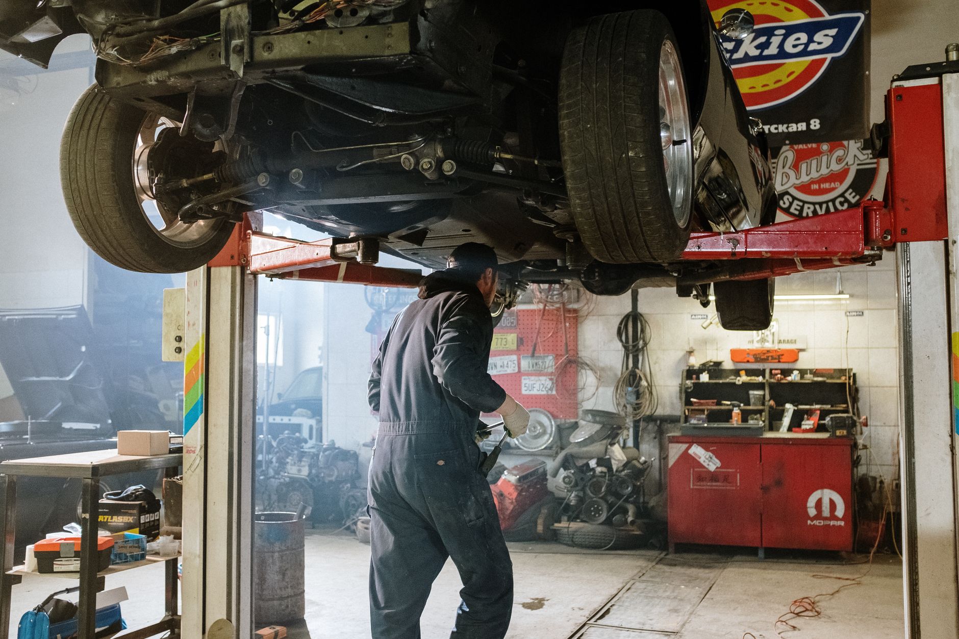 Mechanic working under a car raised on a lift in a repair shop