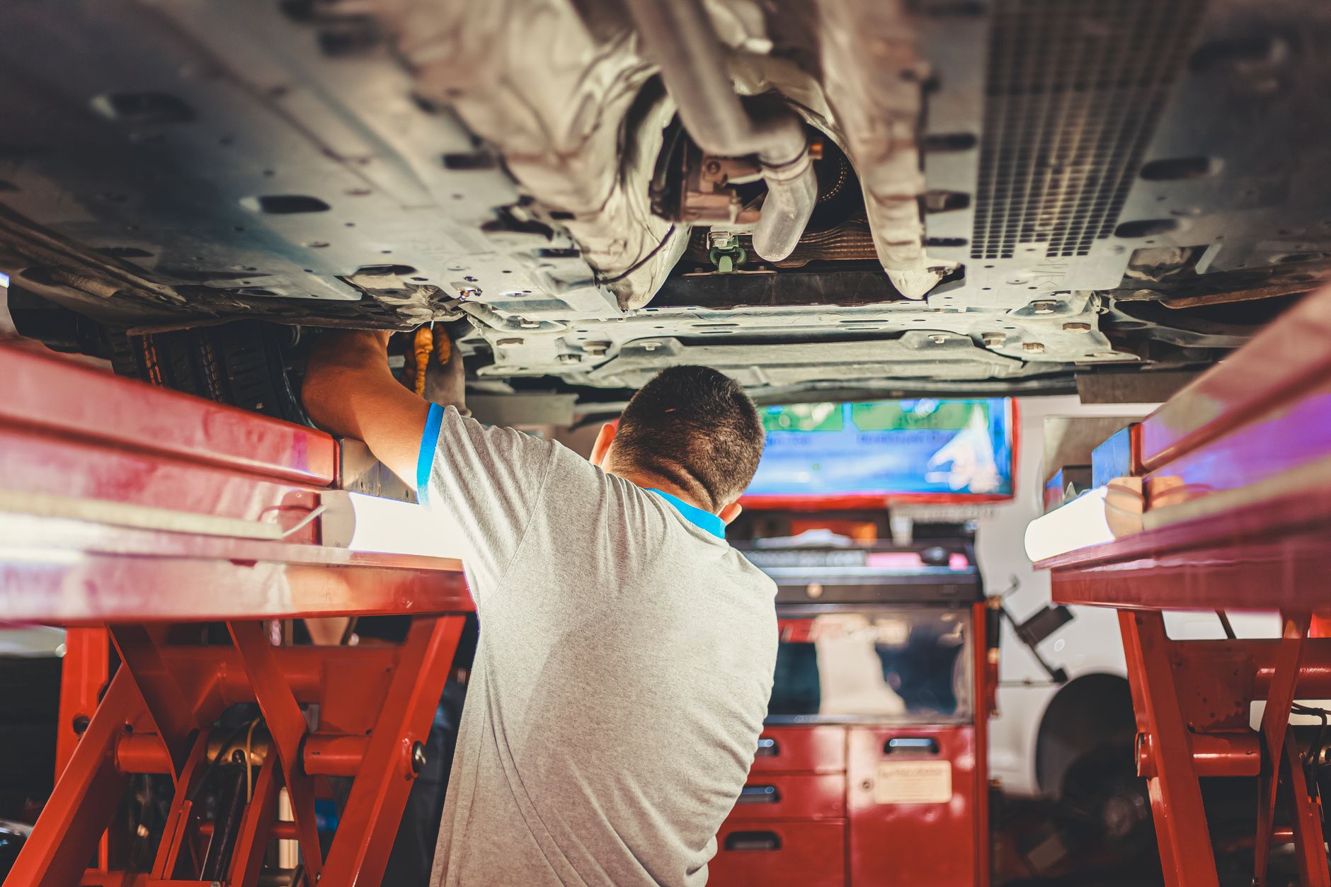 Mechanic working underneath a car raised on a lift