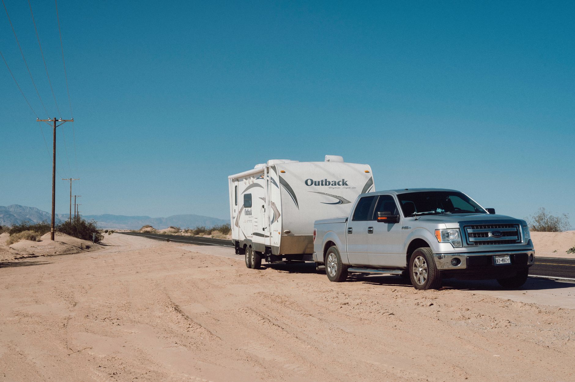 Pickup truck towing a travel trailer on a desert road