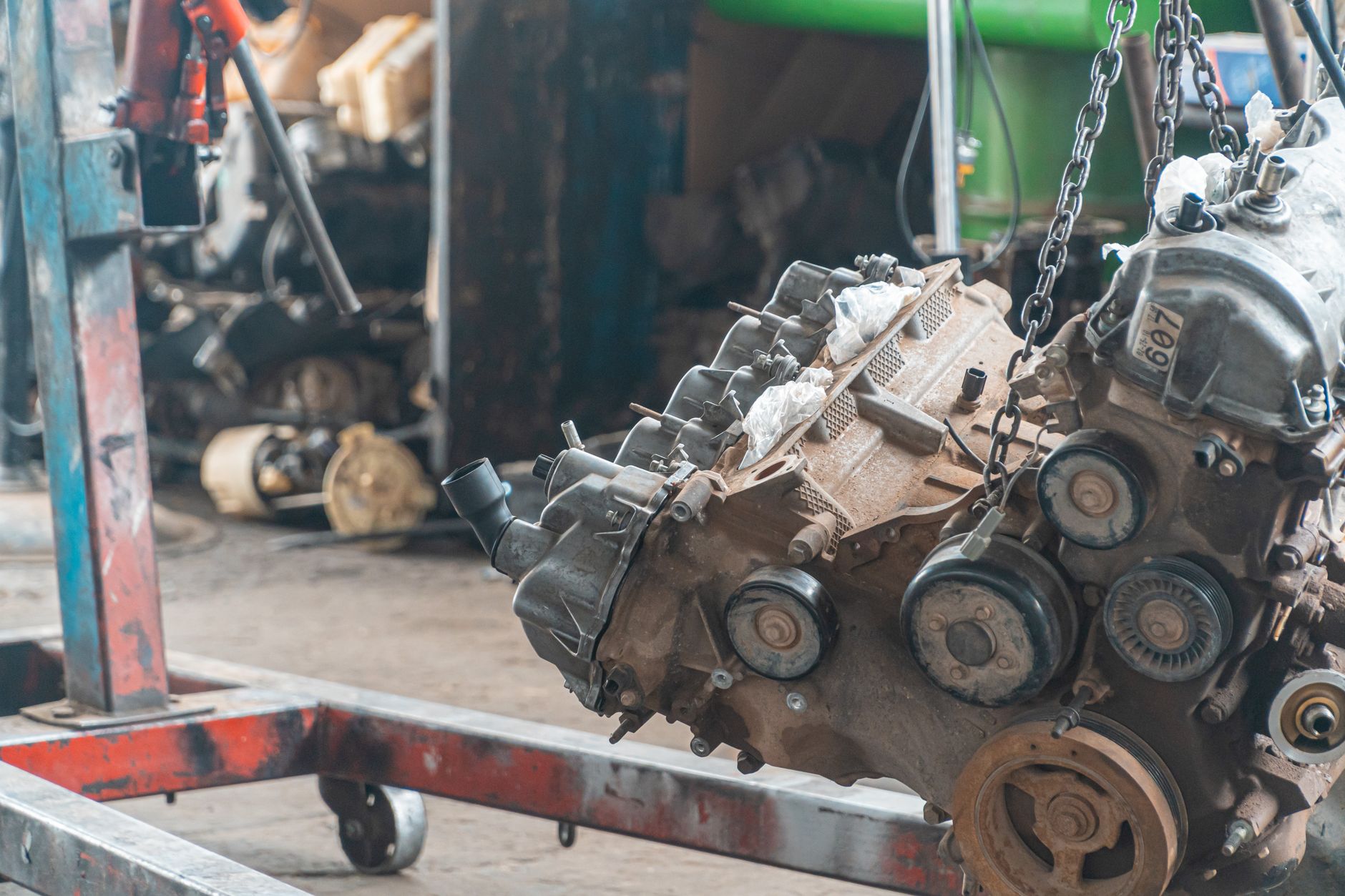 Powertrain hanging from a chain hoist in a repair shop