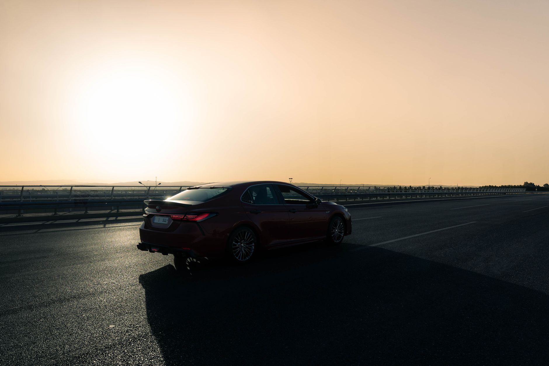 Sedan parked on an open highway at sunset