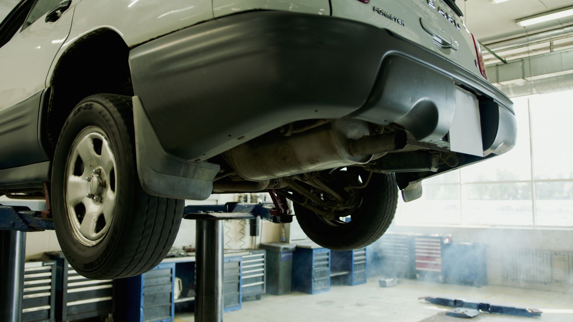 SUV raised on a lift in a repair shop, showing its underside