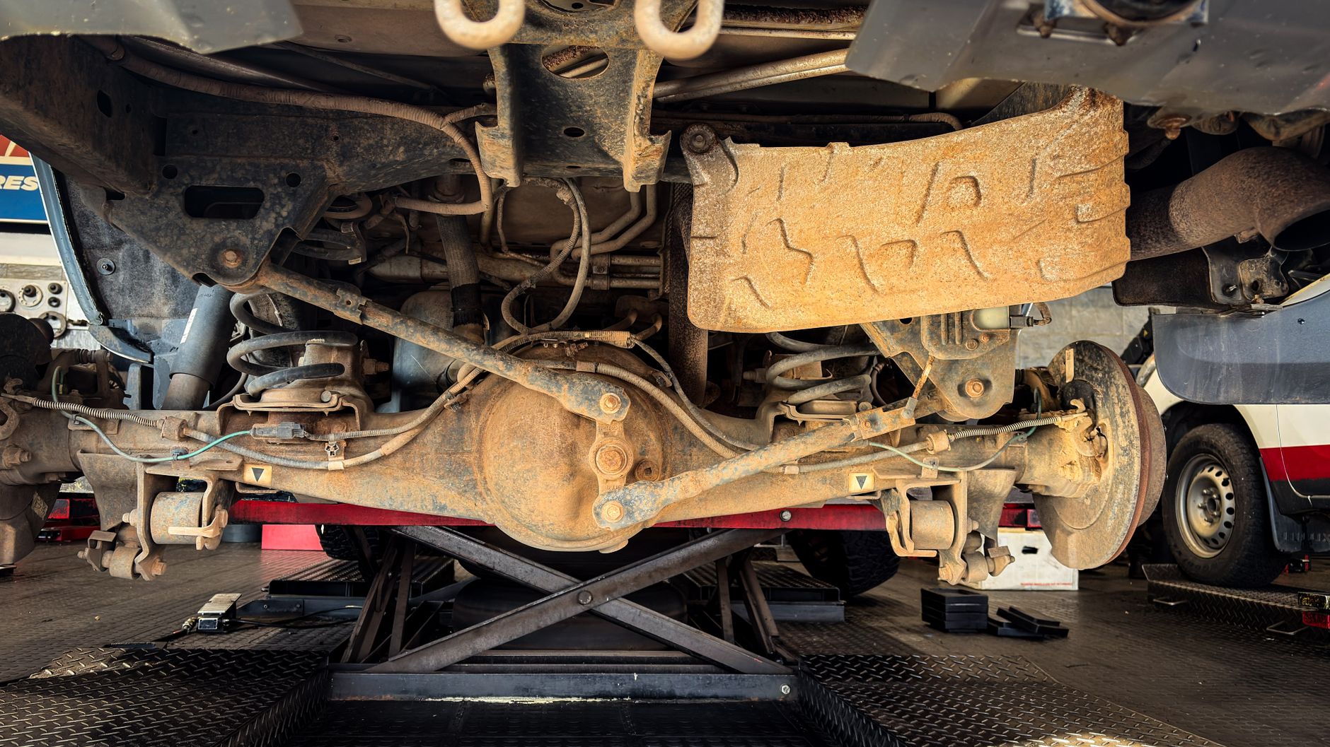 Underside of a truck on a lift showing the transmission and drivetrain
