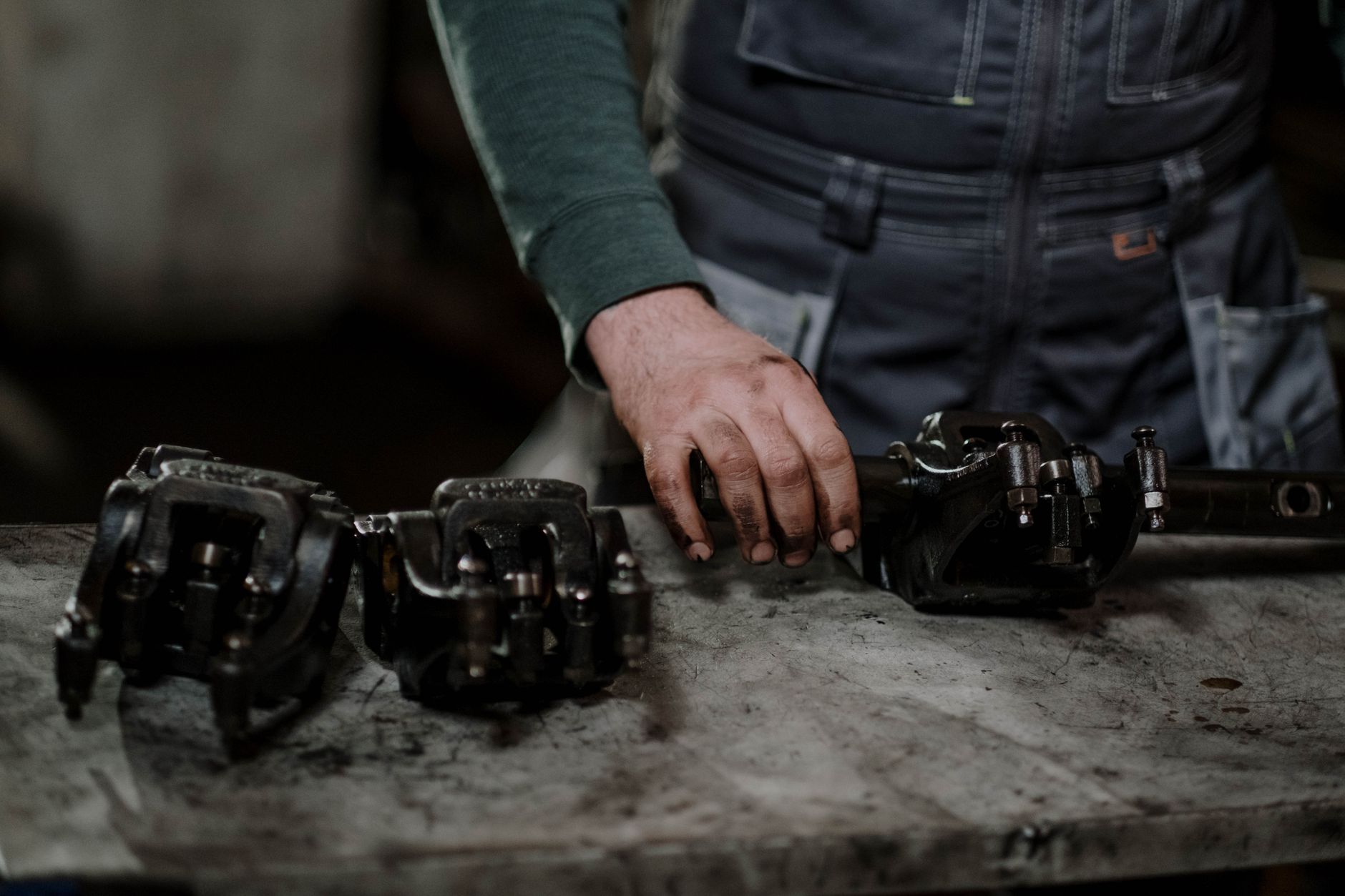 Mechanic with worn drivetrain parts laid out on a shop workbench